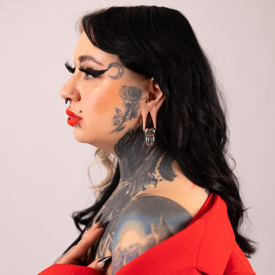 Mujer con tatuajes lleva un peso para orejas negro y plateado, ropa roja