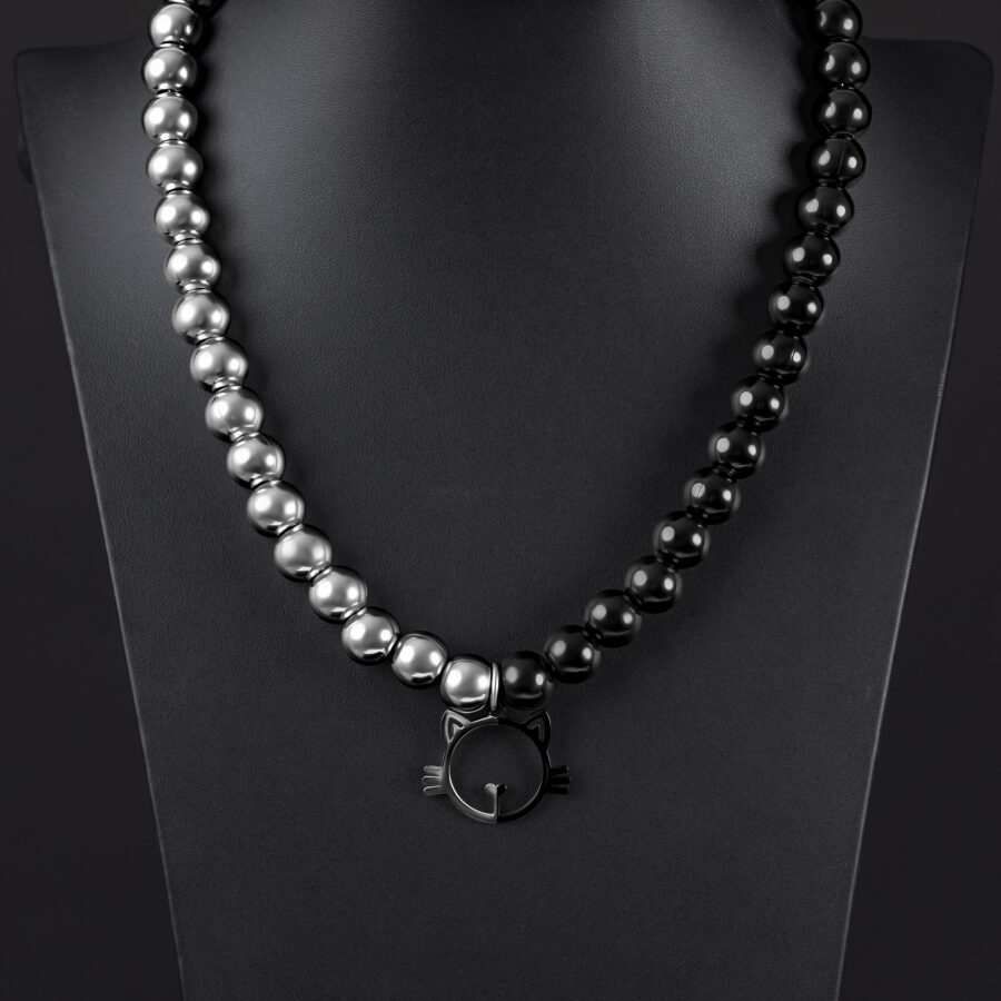 Collar plateado y negro con colgante de gato sobre fondo negro