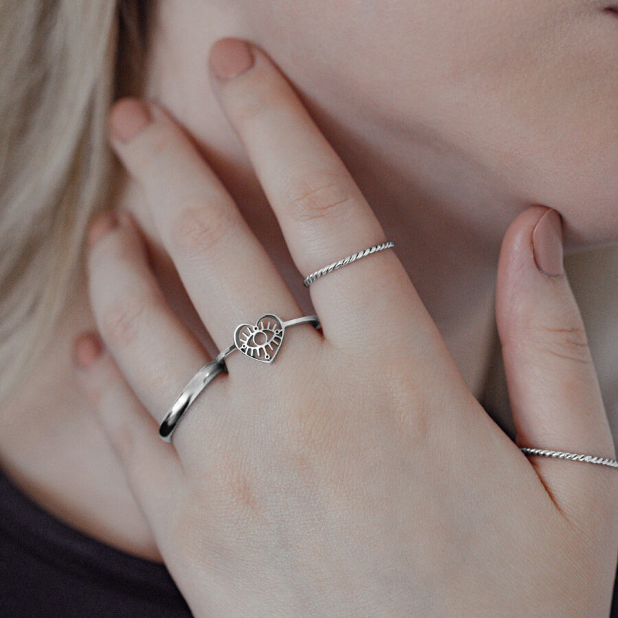 Anillo Eye de plata en acero quirúrgico en mano de mujer, diseño de corazón, primer plano