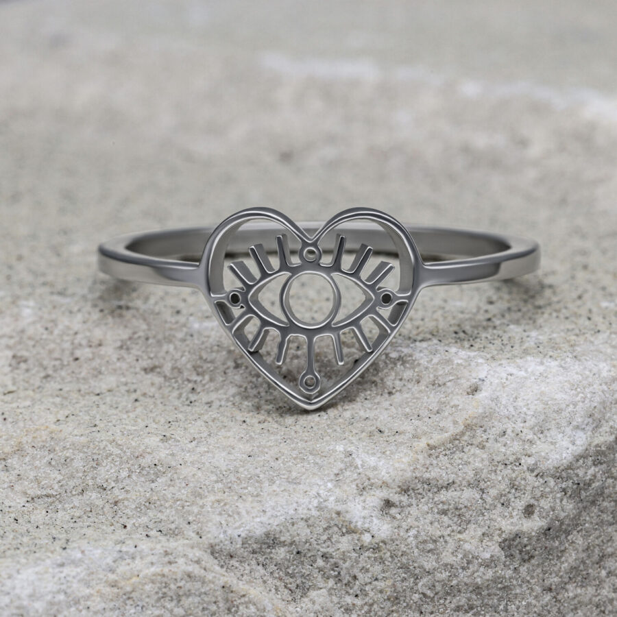 Anillo plateado en forma de corazón con motivo de ojo sobre piedra gris