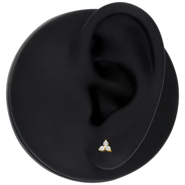 Aro Trinity de 14K Gold con cristales claros sobre modelo de oreja negro