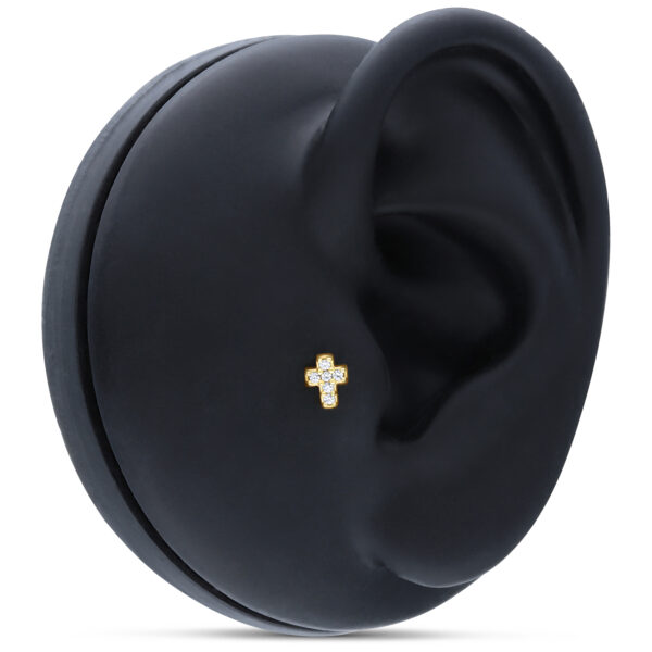 Accesorio cruz dorado con cristales sobre display de oreja negro