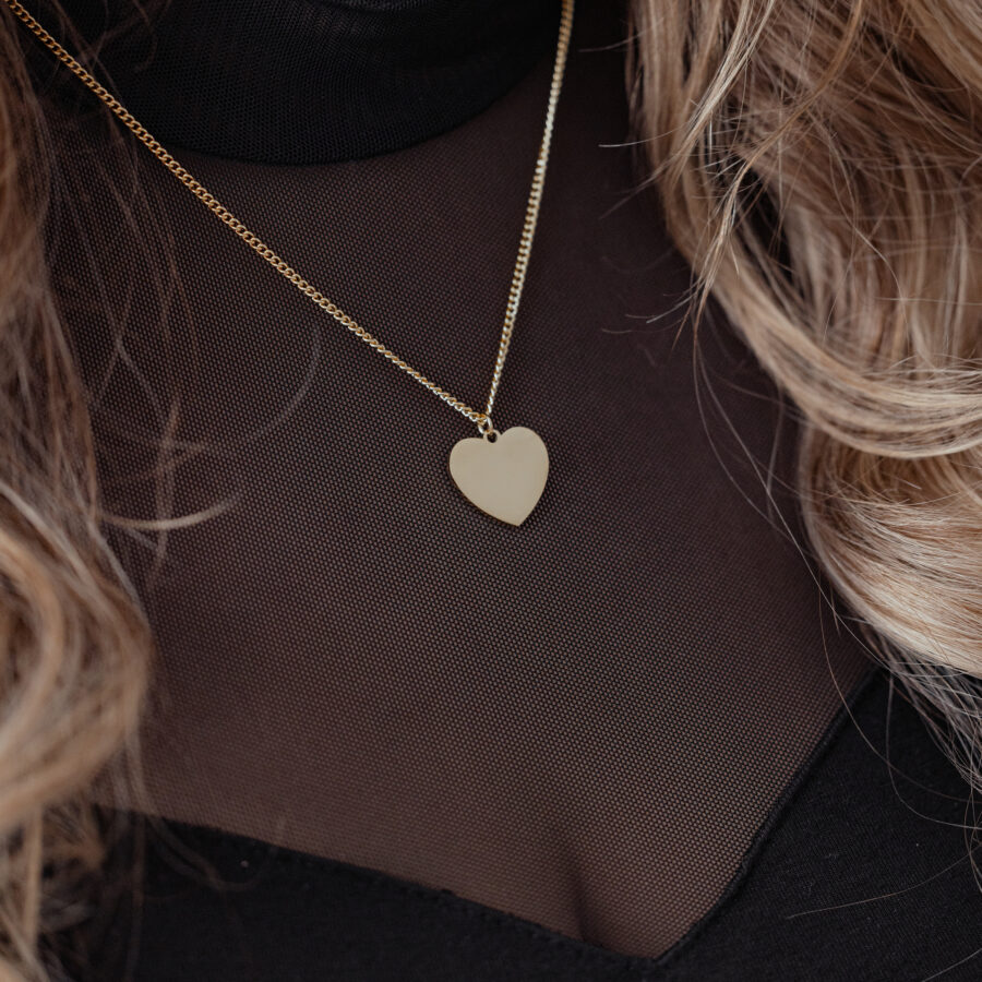 Collar de corazón dorado en cadena delicada sobre prenda negra