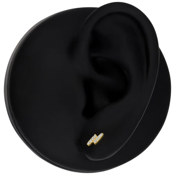 Accesorio dorado de 14K Gold con cristales claros sobre modelo de oreja negro