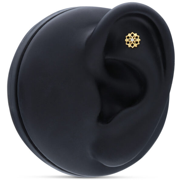 Pequeño accesorio dorado Kaleidoscopio en la oreja sobre fondo negro