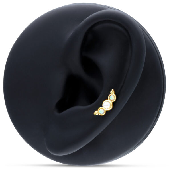 Accesorio de oro 14K con tres perlas de ópalo sintético sobre fondo negro