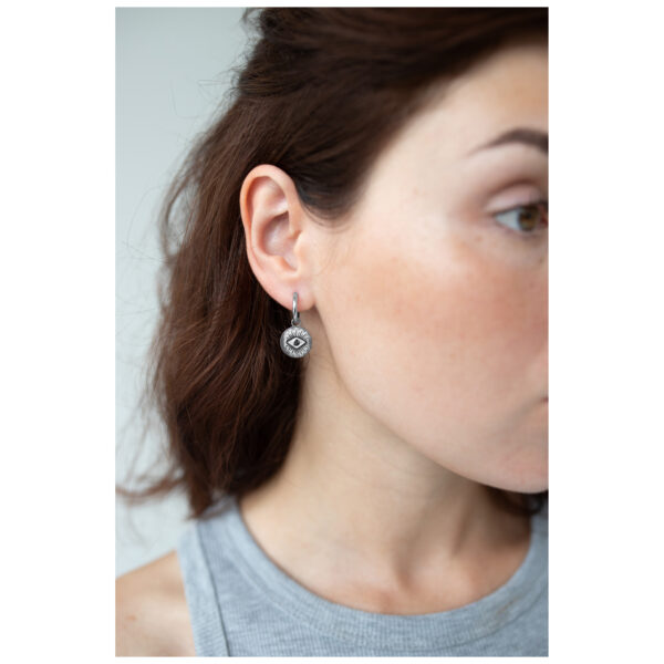Mujer con aros plateados con motivo de ojo, vista lateral