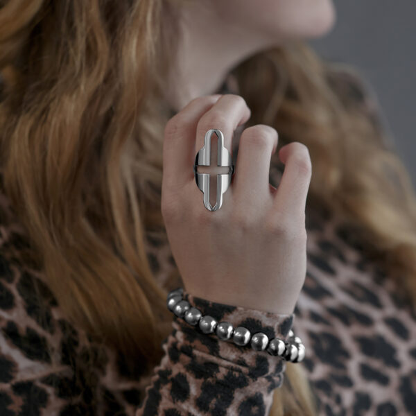 Gran anillo de dedo con diseño de cruz de acero quirúrgico usado en una mano