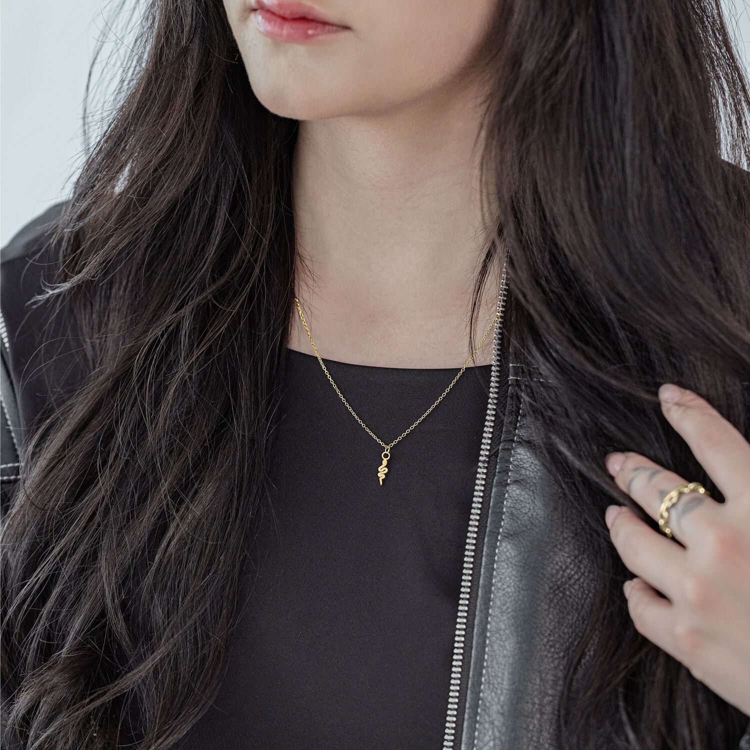 Mujer con cadena Little Snake dorada, atuendo negro, cabello largo