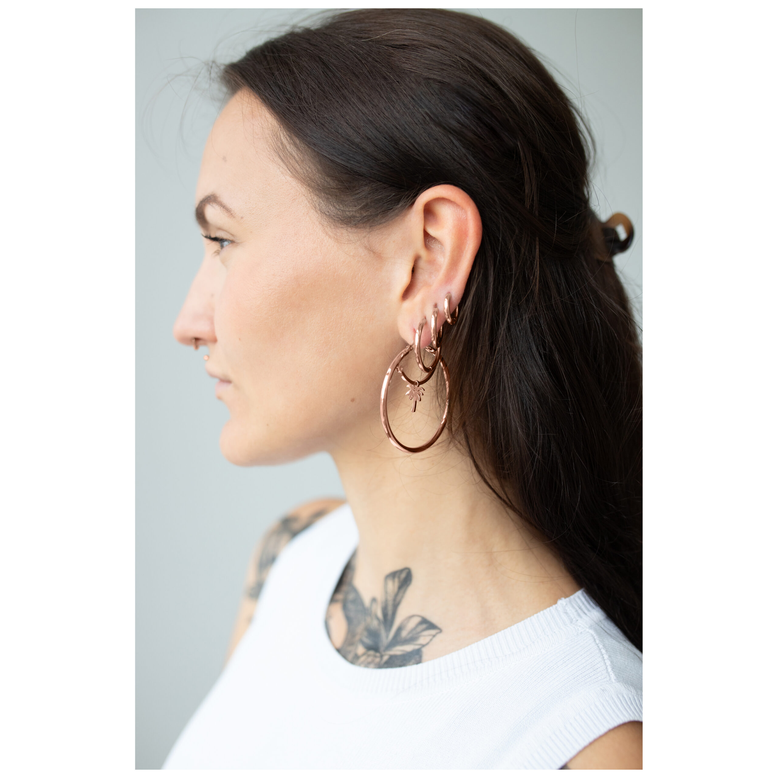 Roségoldene Ohrringe mit Klappverschluss getragen von Frau mit dunklem Haar im Profil