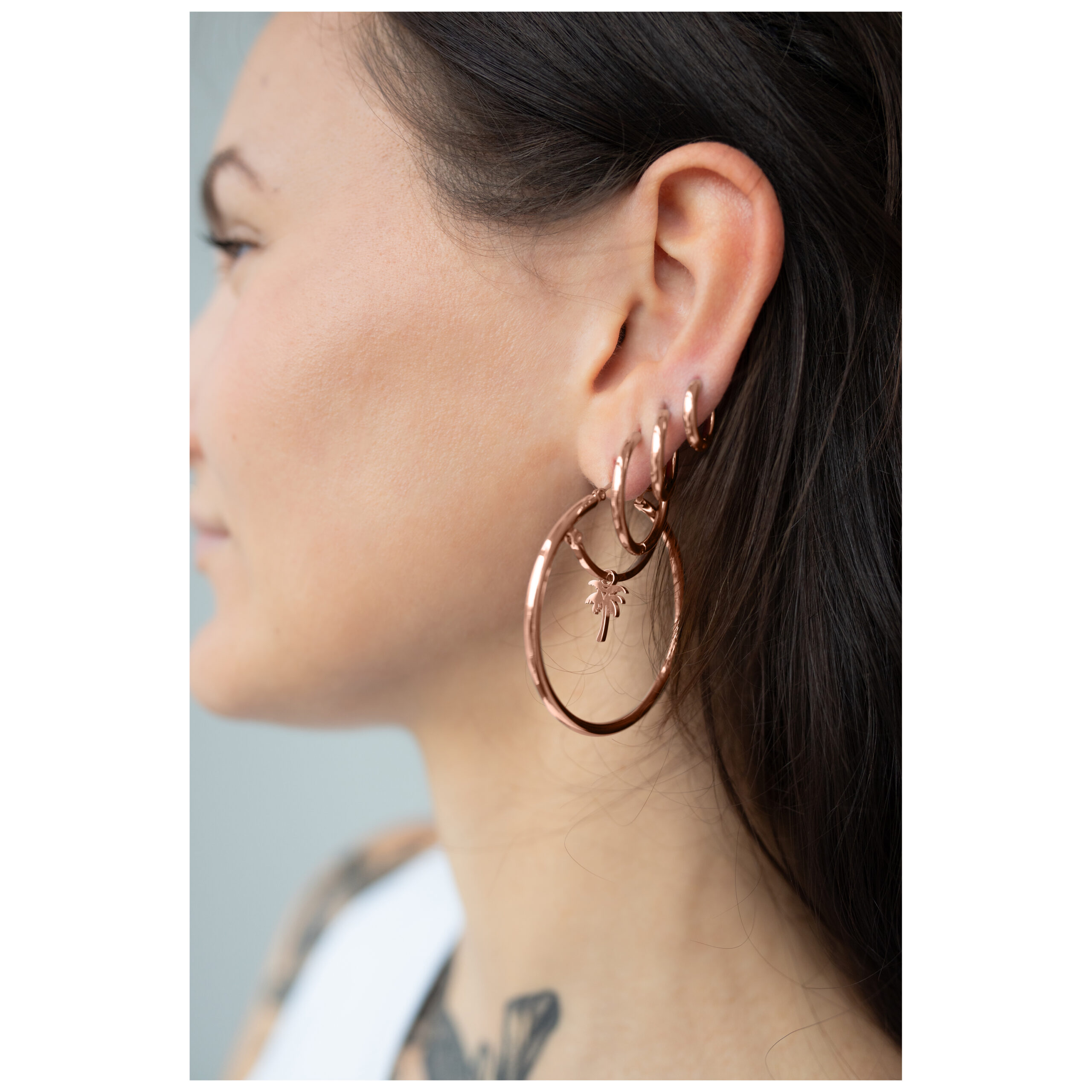 Frau mit großen roségoldenen Ohrringen im Ohr, seitliches Profil