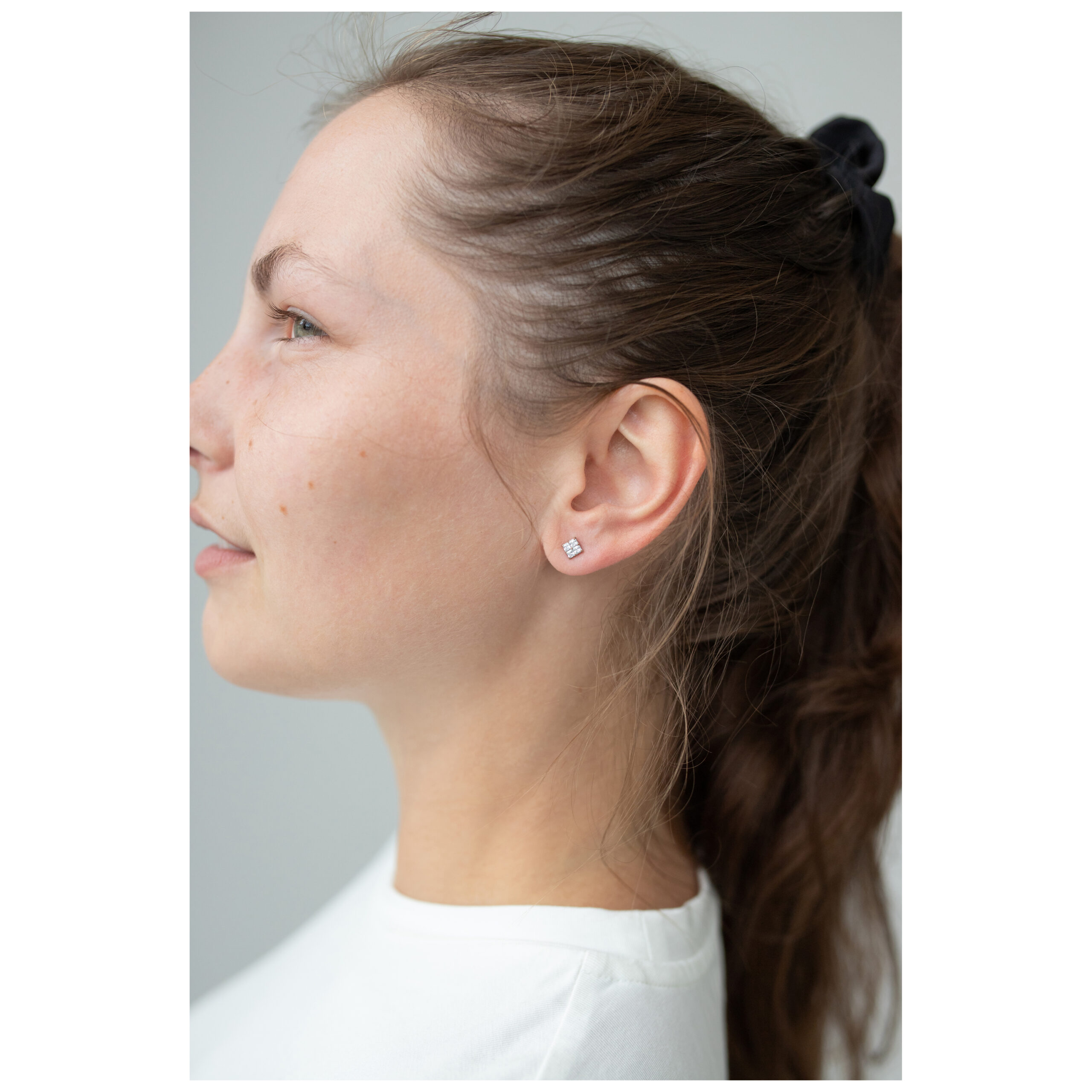 Roségoldene Kristall-Ohrstecker im Profil Frau mit roségoldenem Kristall-Ohrstecker auf schlichtem Hintergrund