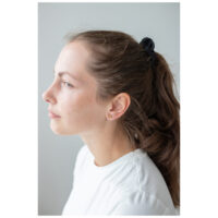 Mujer con pendientes de corazón dorado y blusa blanca en perfil