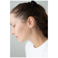 Frau mit Roségold Ohrstecker Double Beam Crystal vor grauem Hintergrund