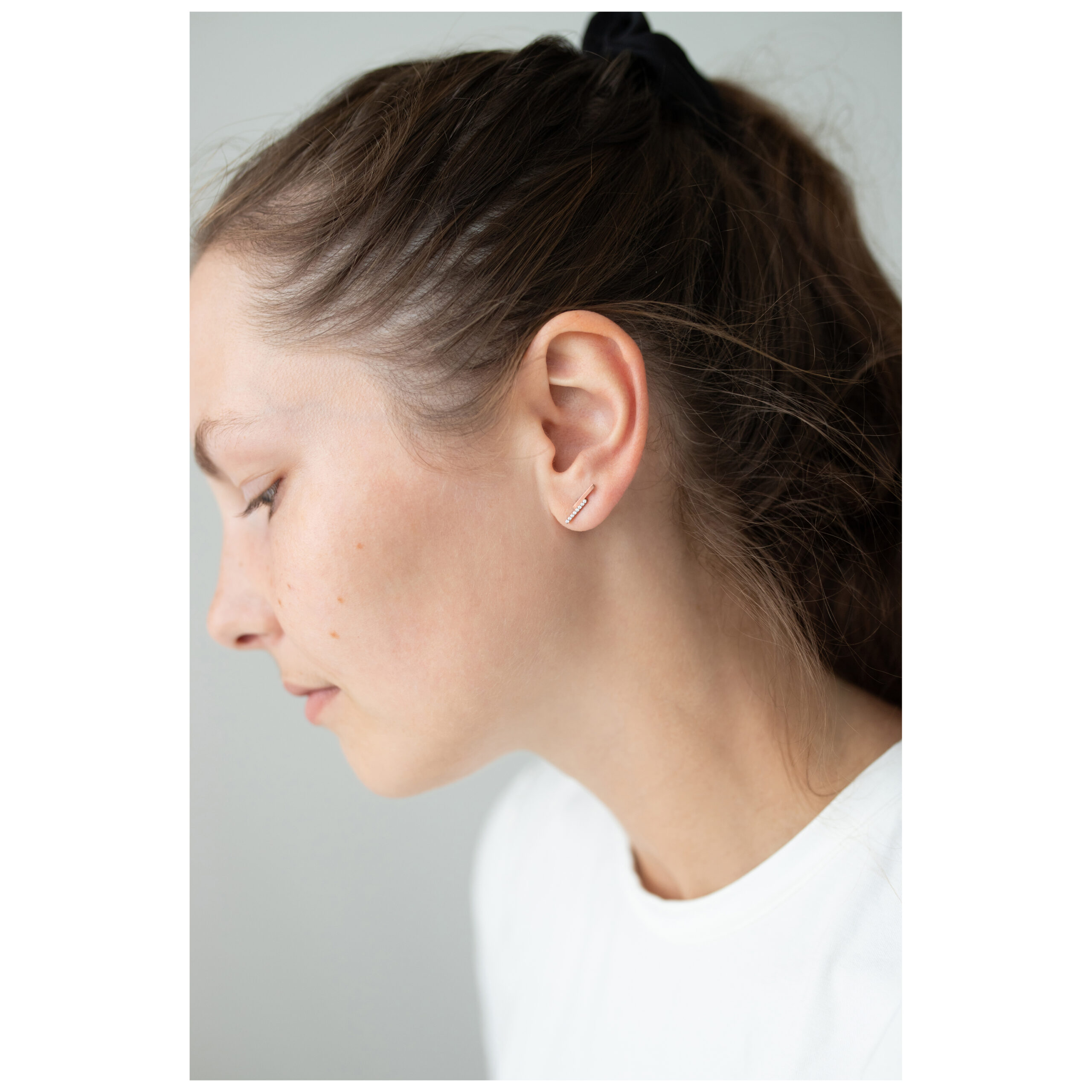 Frau mit Roségold Ohrstecker Double Beam Crystal vor grauem Hintergrund