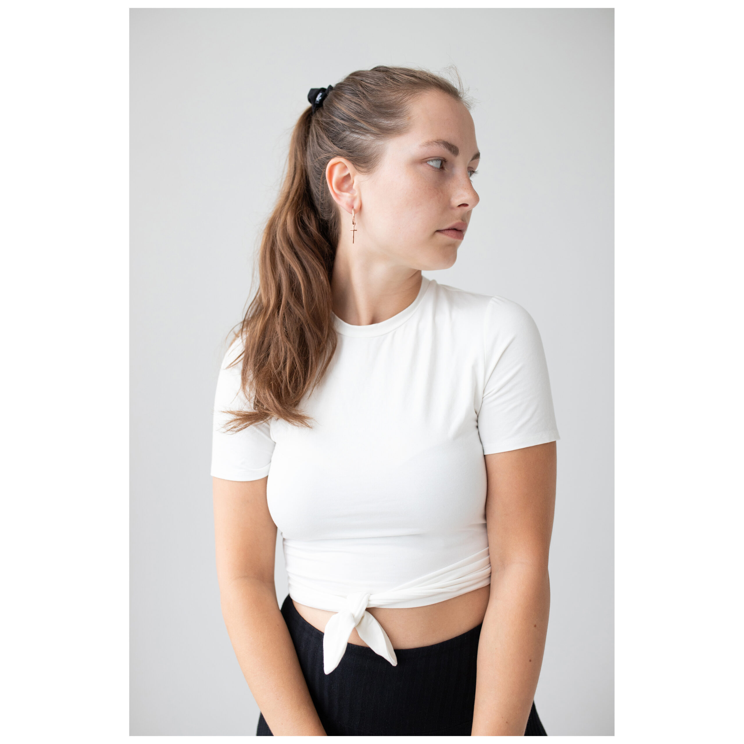 Roségoldene Little Cross Hoops Ohrringe Frau mit langen Haaren trägt roségoldene Little Cross Hoops Ohrringe