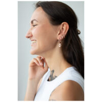 Frau mit roségoldenen Anker-Ohrringen, lächelnd, seitliches Profil
