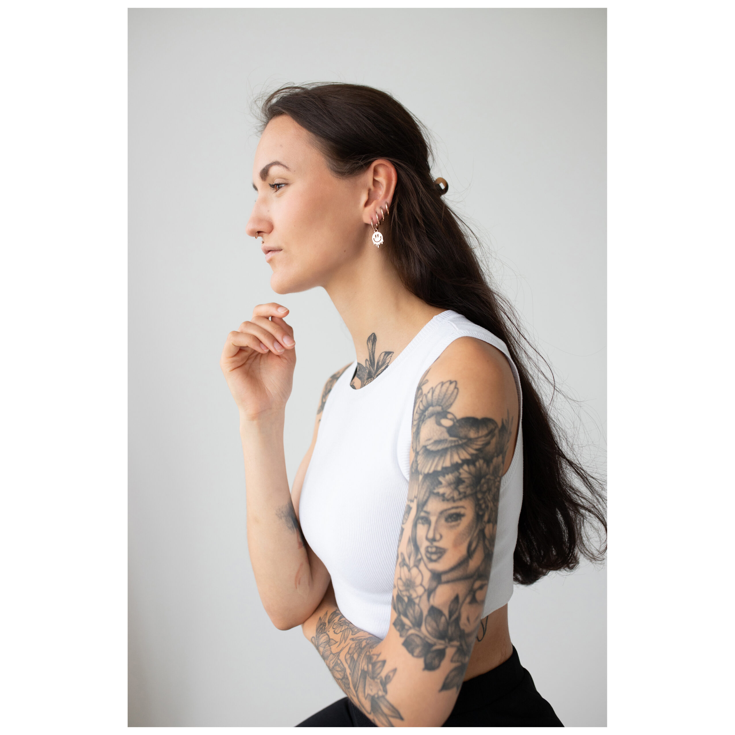 Frau mit tätowiertem Arm trägt roségoldene Smiley-Creolen