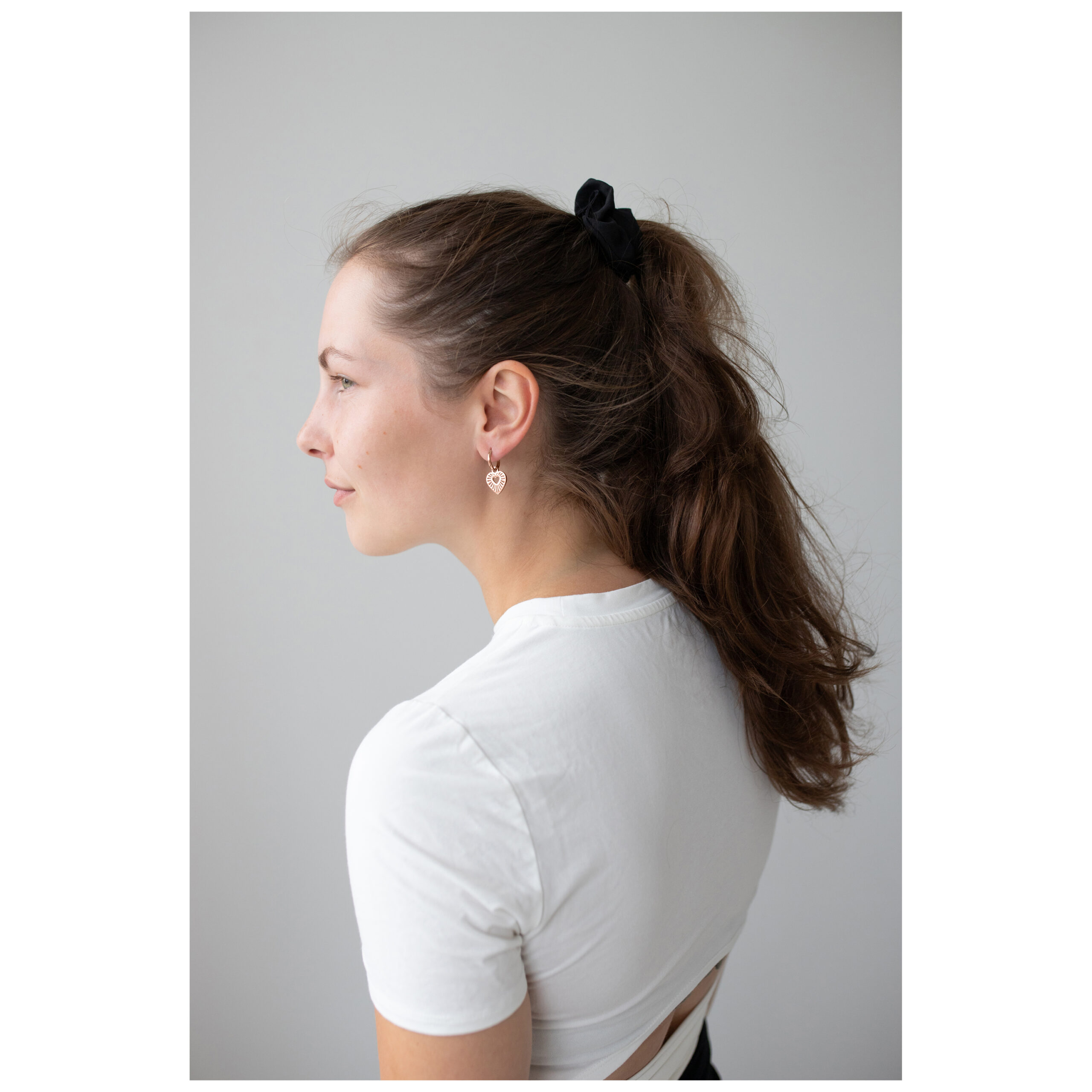 Model mit roségoldenen Herz-Ohrringen und weißem Shirt