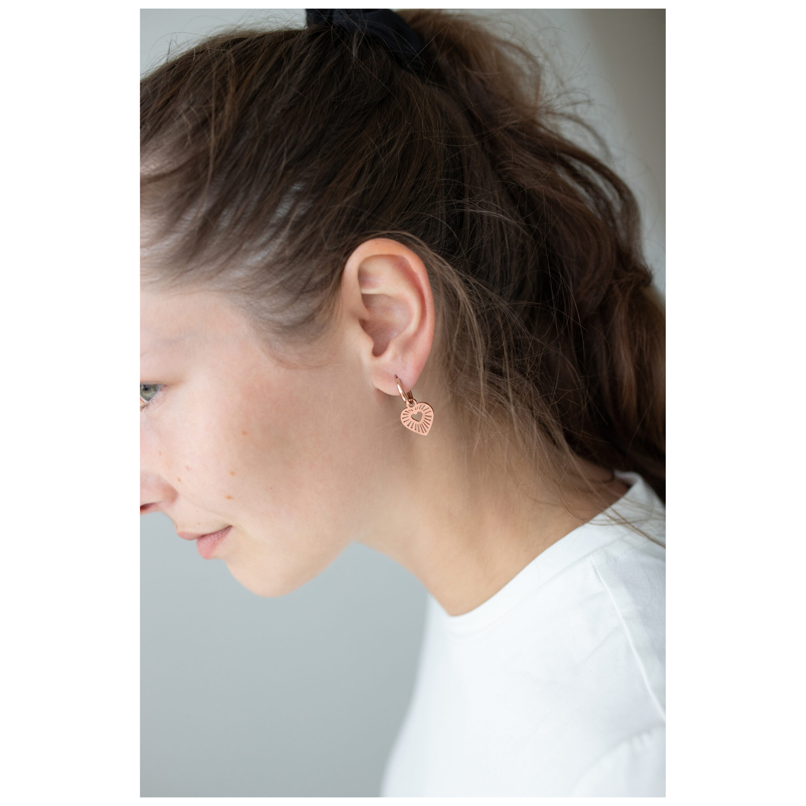 Frau mit roségoldenen Herz-Ohrringen, seitliches Profil