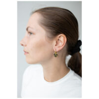 Mujer con aros Little Soulmate dorados frente a un fondo gris