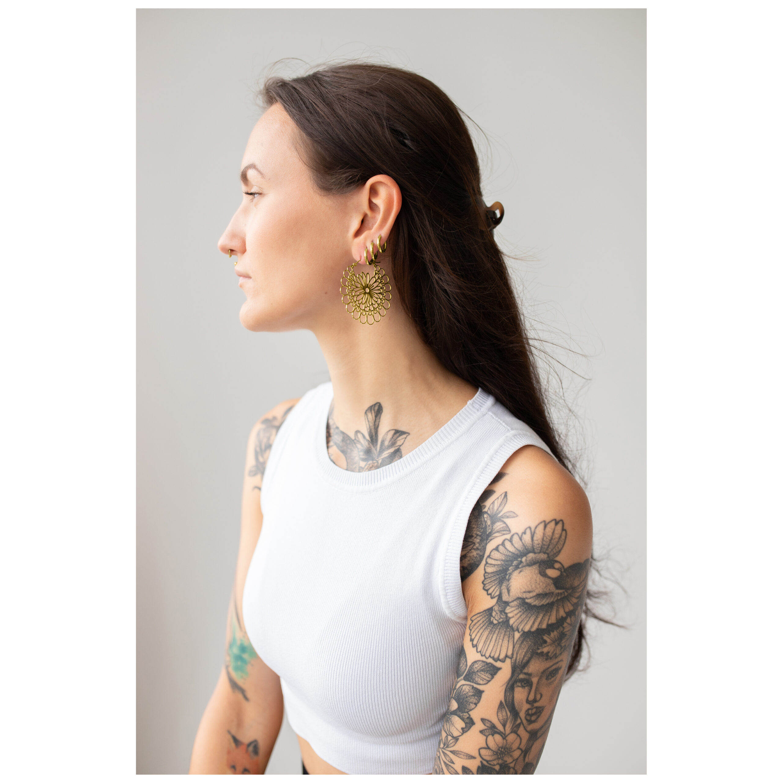 Aros Daisy Dorados en Set Mujer con cabello largo lleva aros Daisy dorados, top blanco