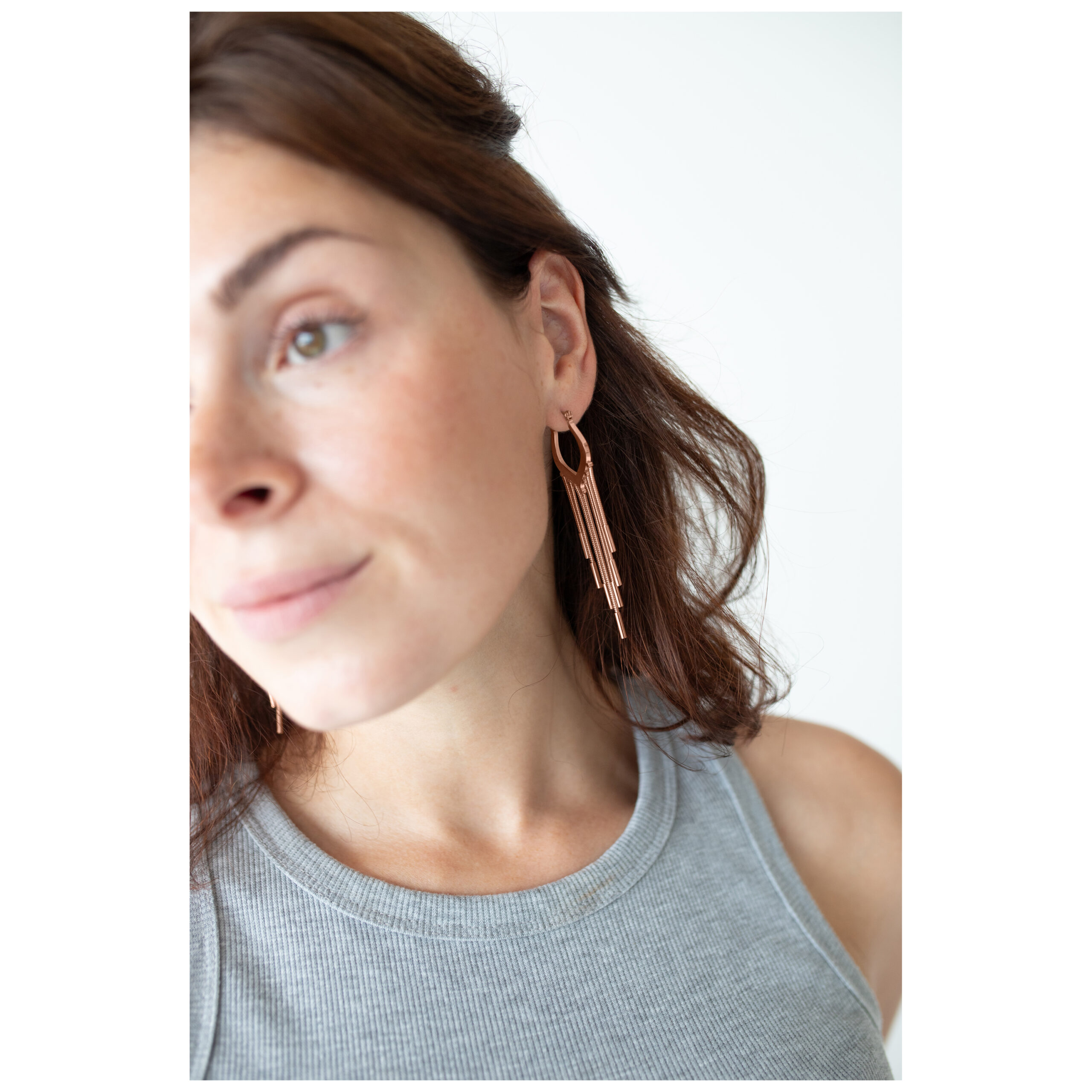 Frau mit roségoldenen Snakechain Hoops Ohrringen vor weißem Hintergrund