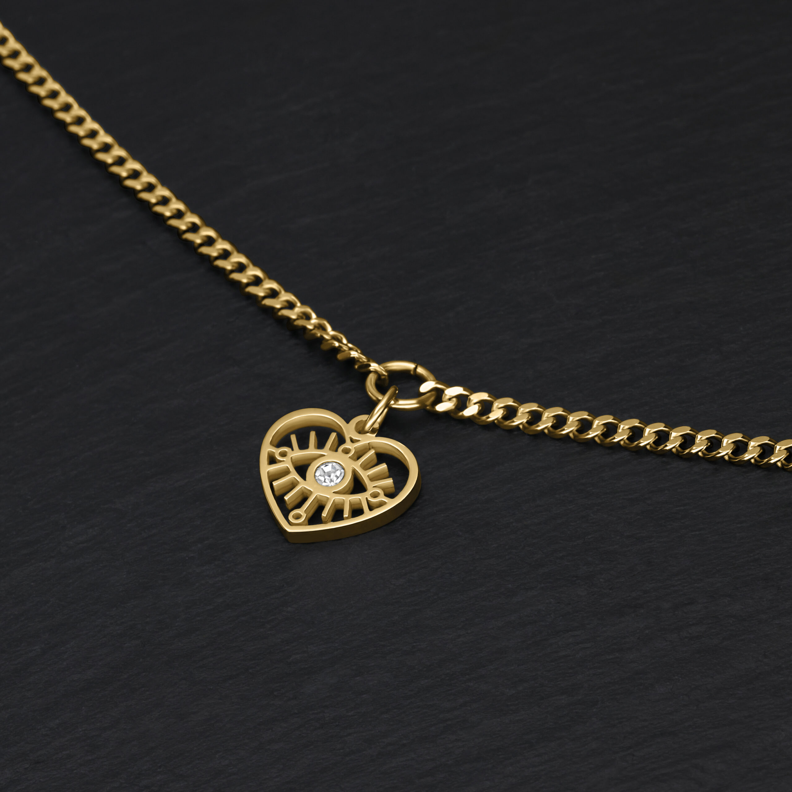 Pulsera dorada con colgante de corazón sobre fondo negro