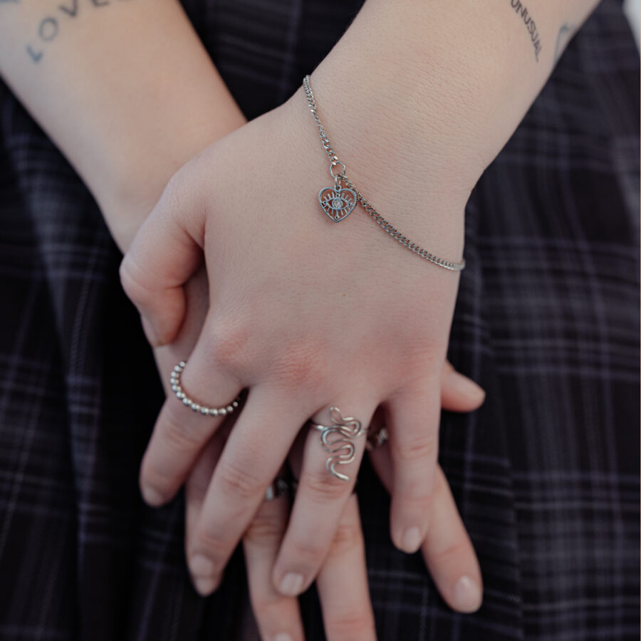 Pulsera de plata con colgante de corazón en la muñeca, llevada por una persona.
