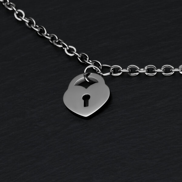 Pulsera de plata con colgante de candado en forma de corazón sobre fondo negro