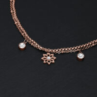 Roségoldenes Armband mit Blumenanhänger und klaren Kristallen auf schwarzem Hintergrund