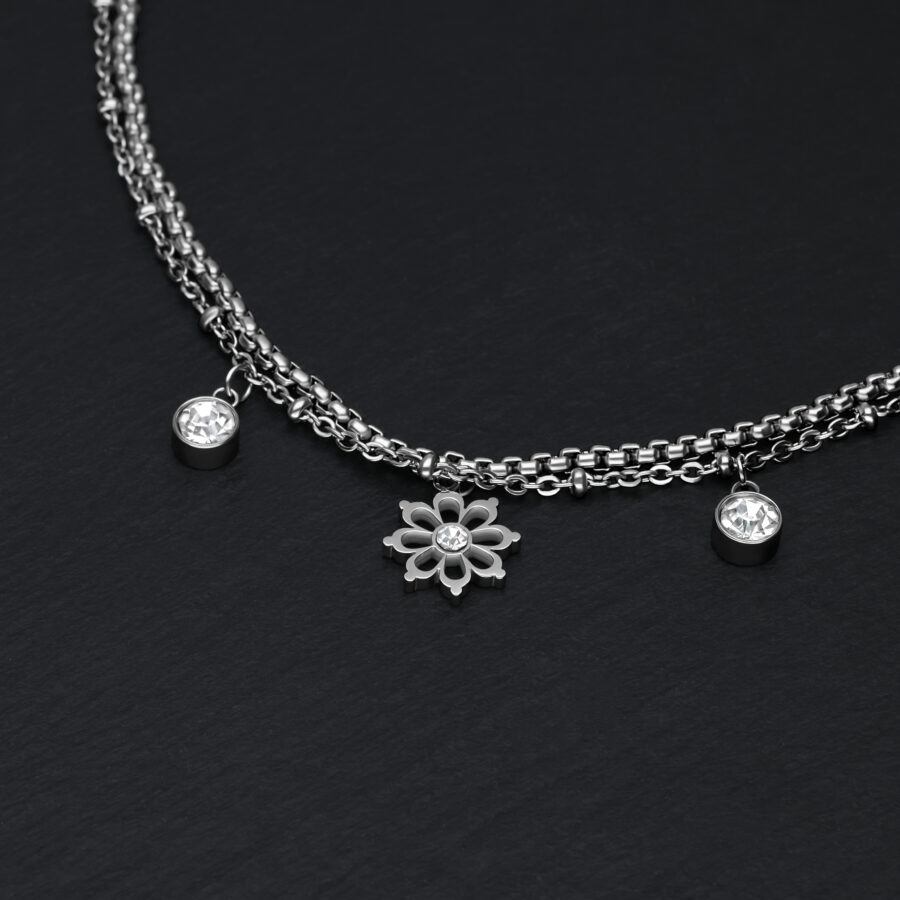 Pulsera de plata sobre fondo negro con colgantes florales y cristales