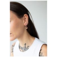 Frau mit roségoldenen Little Bulldog Hoops Ohrringen auf hellem Hintergrund