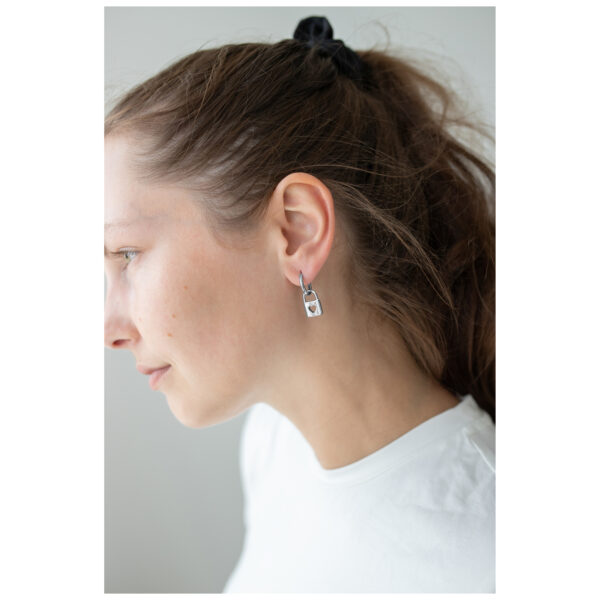 Mujer lleva pendientes Little Lock Hoops plateados sobre fondo blanco