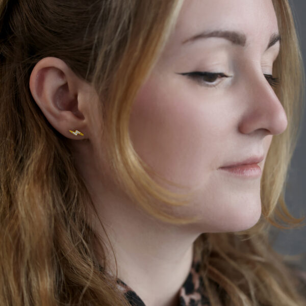 Mujer con barra para oreja con cristal dorado Flashlight, fondo gris