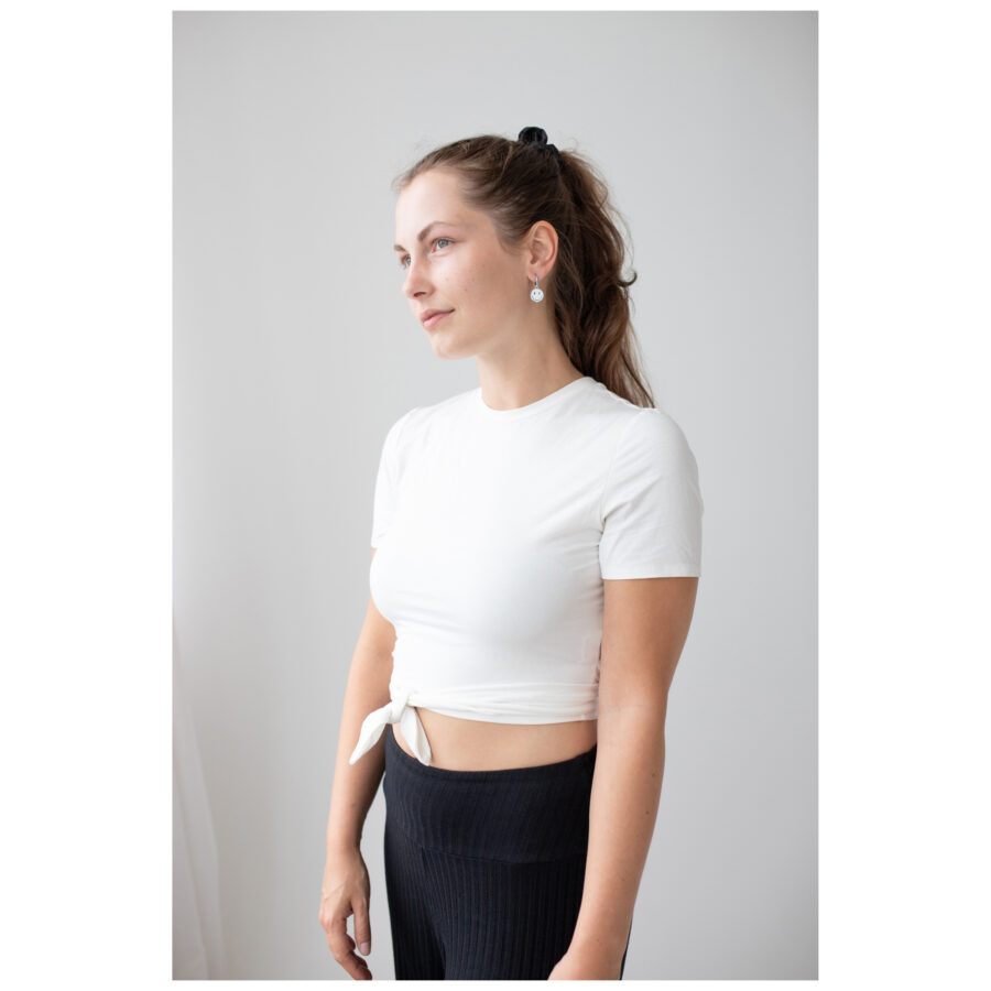 Mujer con camiseta blanca lleva Little White Smiley Hoops frente a fondo blanco