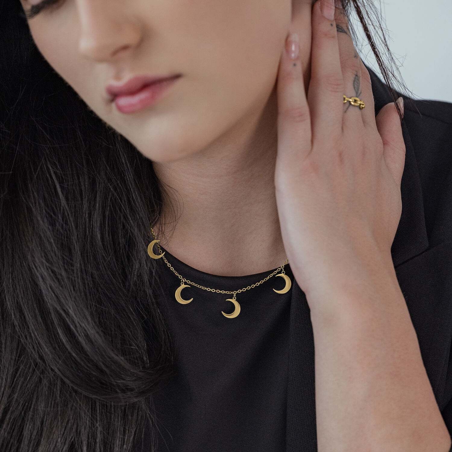 Collar dorado con pequeños colgantes de luna sobre fondo negro