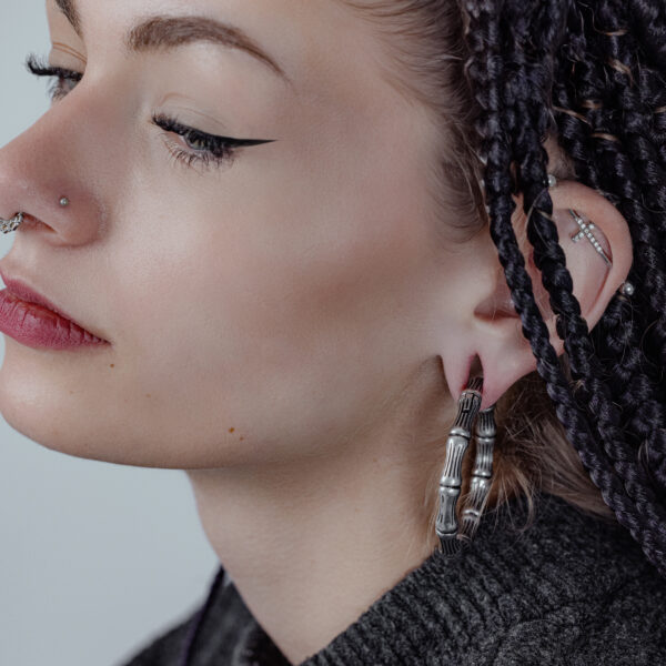 Mujer con trenzas negras lleva un peso para oreja Bonechain plateado