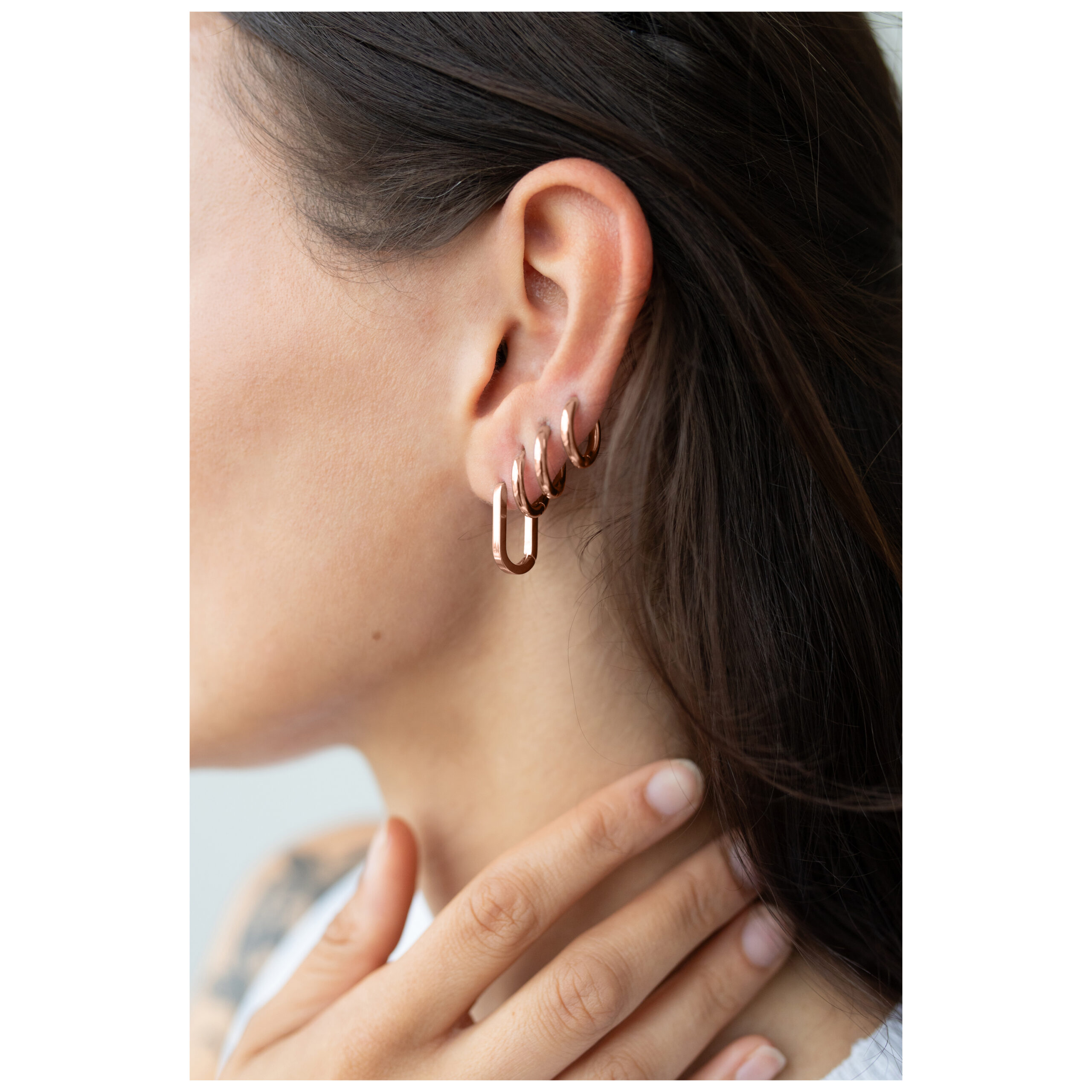 Roségoldene Oval Basic Hoops am Ohr einer Frau, Nahaufnahme