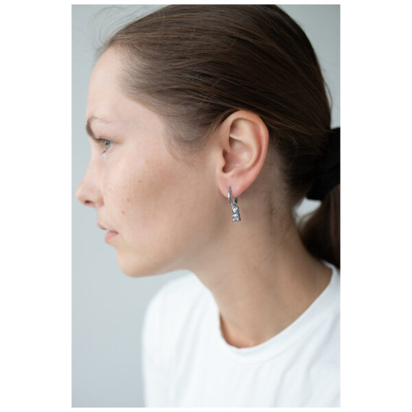 Mujer con pendientes de ositos de goma plateados, perfil lateral