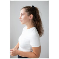 Frau mit langen braunen Haaren trägt roségoldene Creolen vor grauem Hintergrund