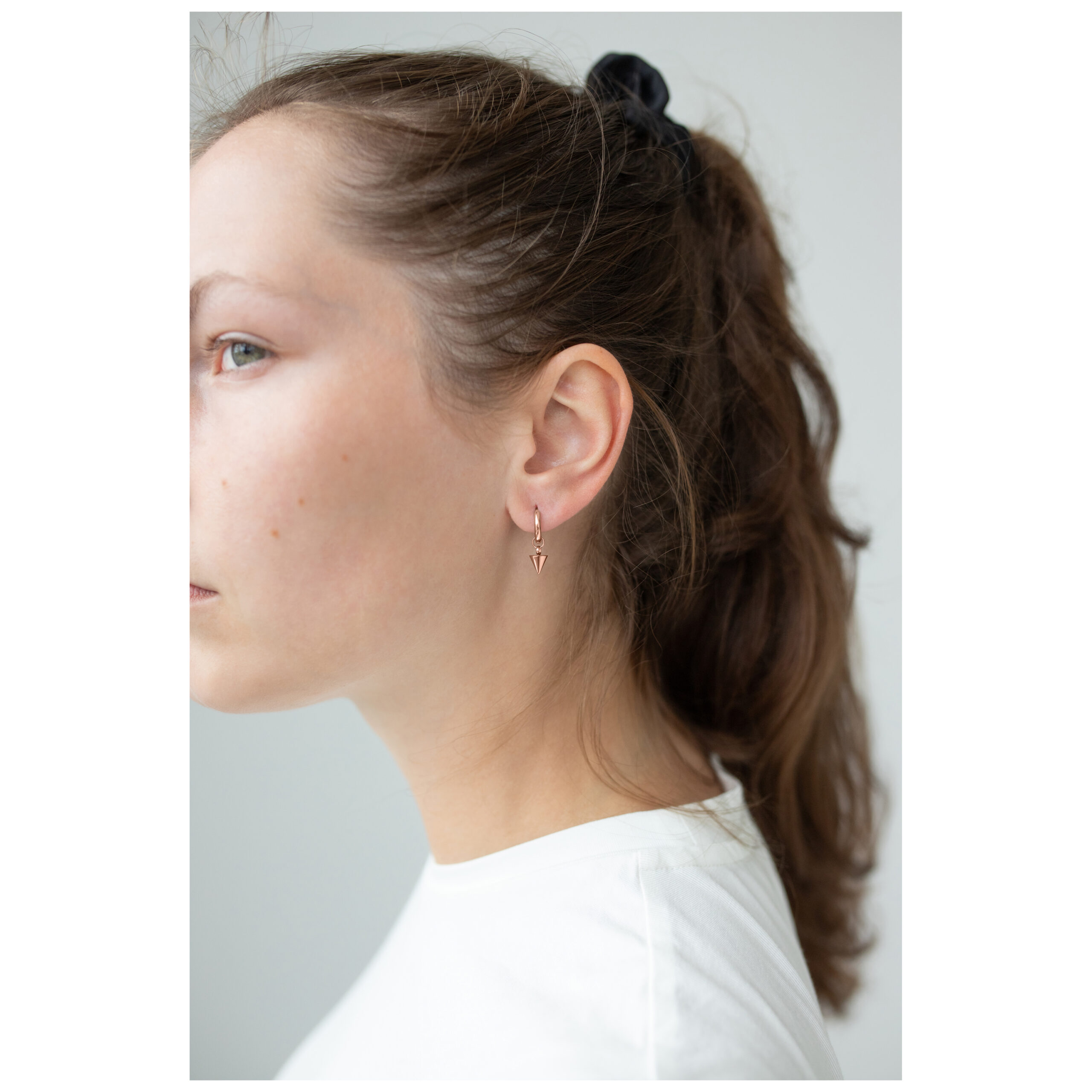 Frau mit braunen Haaren trägt roségoldene Little Short Spike Hoops Ohrringe