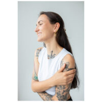 Aros Dorados Little Moonchild Mujer con aros dorados Little Moonchild y tatuajes, sonriendo
