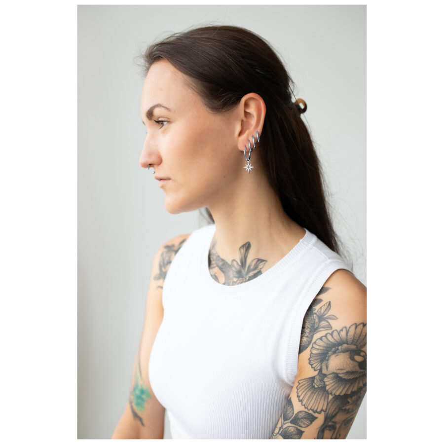 Mujer con Little Polar Star Hoops plateados frente a un fondo claro