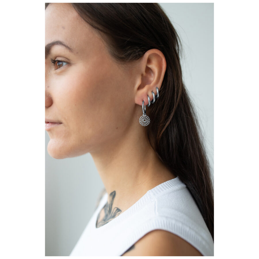 Pendientes Mandala plateados en la oreja izquierda de una mujer, perfil lateral.