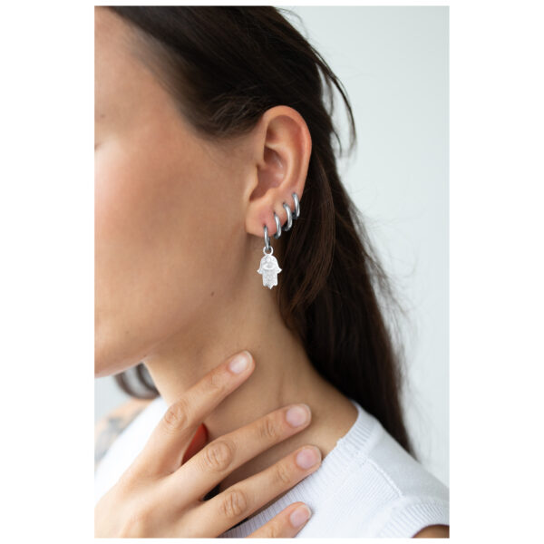 Primer plano de una mujer con aretes de Little Hamsa Hand Hoops de plata adornando su oreja