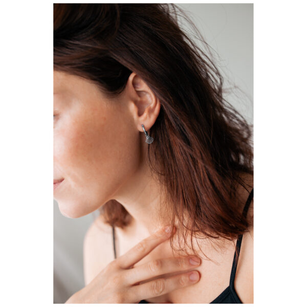 Pendientes plateados en forma de concha en una oreja con cabello castaño y piel clara