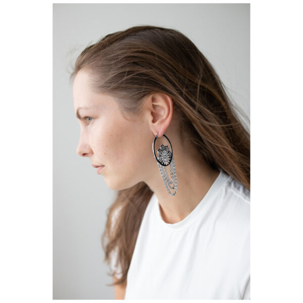 Mujer con cabello largo lleva pendientes La Fleur Hoops en negro y plata