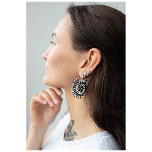 Mujer con aros Floral Nautilus en plata y oro sobre fondo neutro