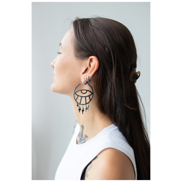 Mujer con cabello largo lleva grandes pendientes Thunderflash Eye Hoops negros de lado